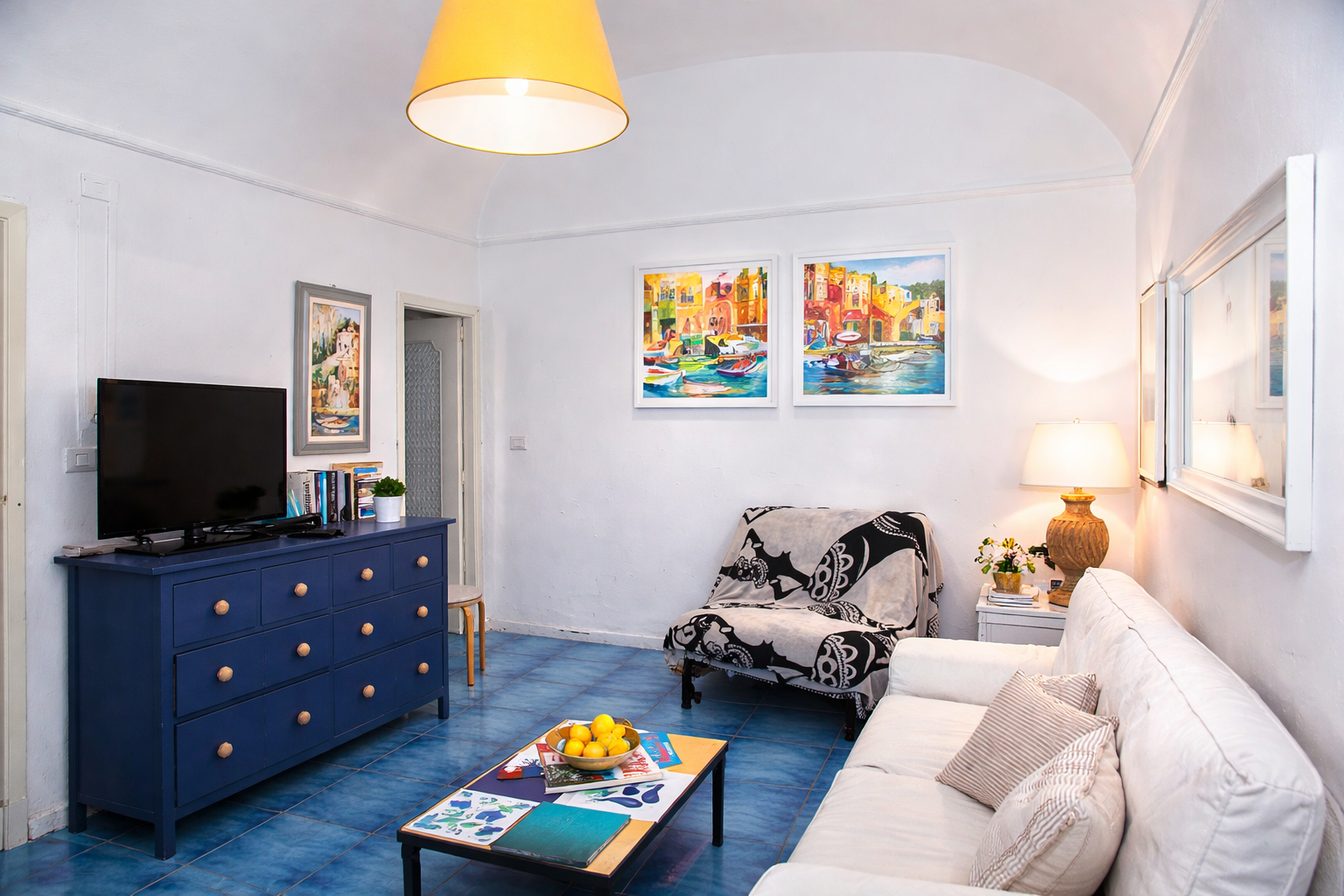 Salotto di AMALFI Sea House con divano bianco, cassettiera blu e porta aperta sul balcone con vista mare - soggiorno panoramico Amalfi